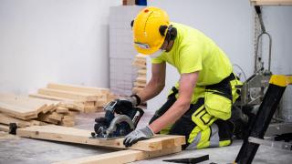 Rakentaja leikkaa moottorisahalla lautaa.