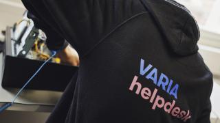 Varian tieto- ja viestintätekniikan opiskelija korjaa konessa helpdesk-huppari päällä. 