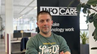 Jimmy Kurvinen Infocaren tiloissa katsoo kameraan hymyillen.