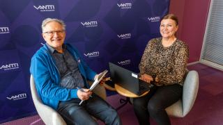 Keijo Mikkonen ja Minna Tuomi istuvat tietokoneen ja lehtiön ääressä hymyillen.