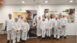 Ryhmä vierailijoita valkoisissa suoja-asuissa HKScanin tiloissa.