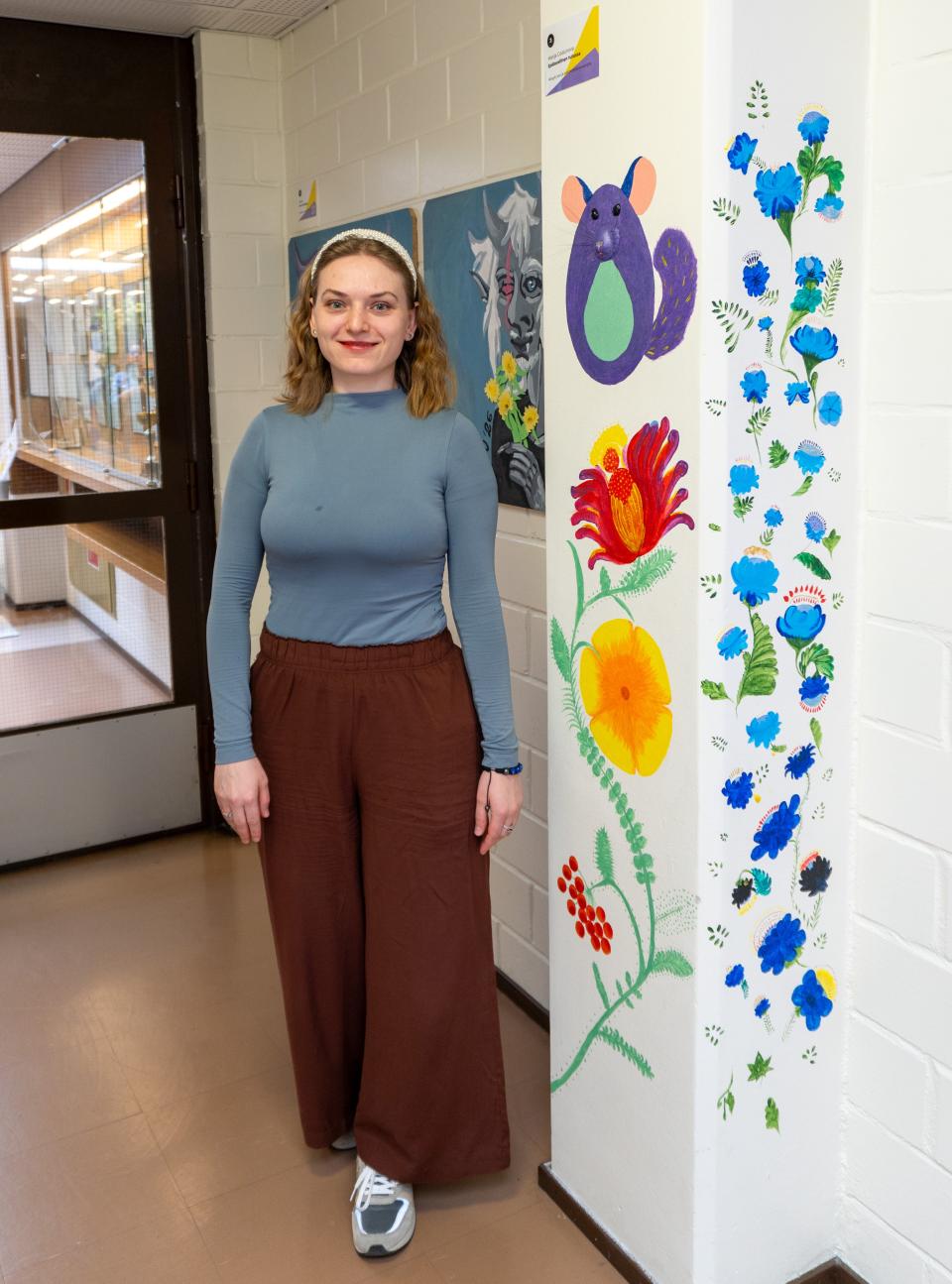 Marija seisoo hymyillen taideteoksensa vieressä.