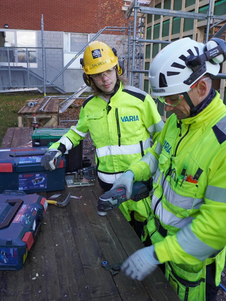 Opettaja opastaa Oskaria työvälineiden käytössä.